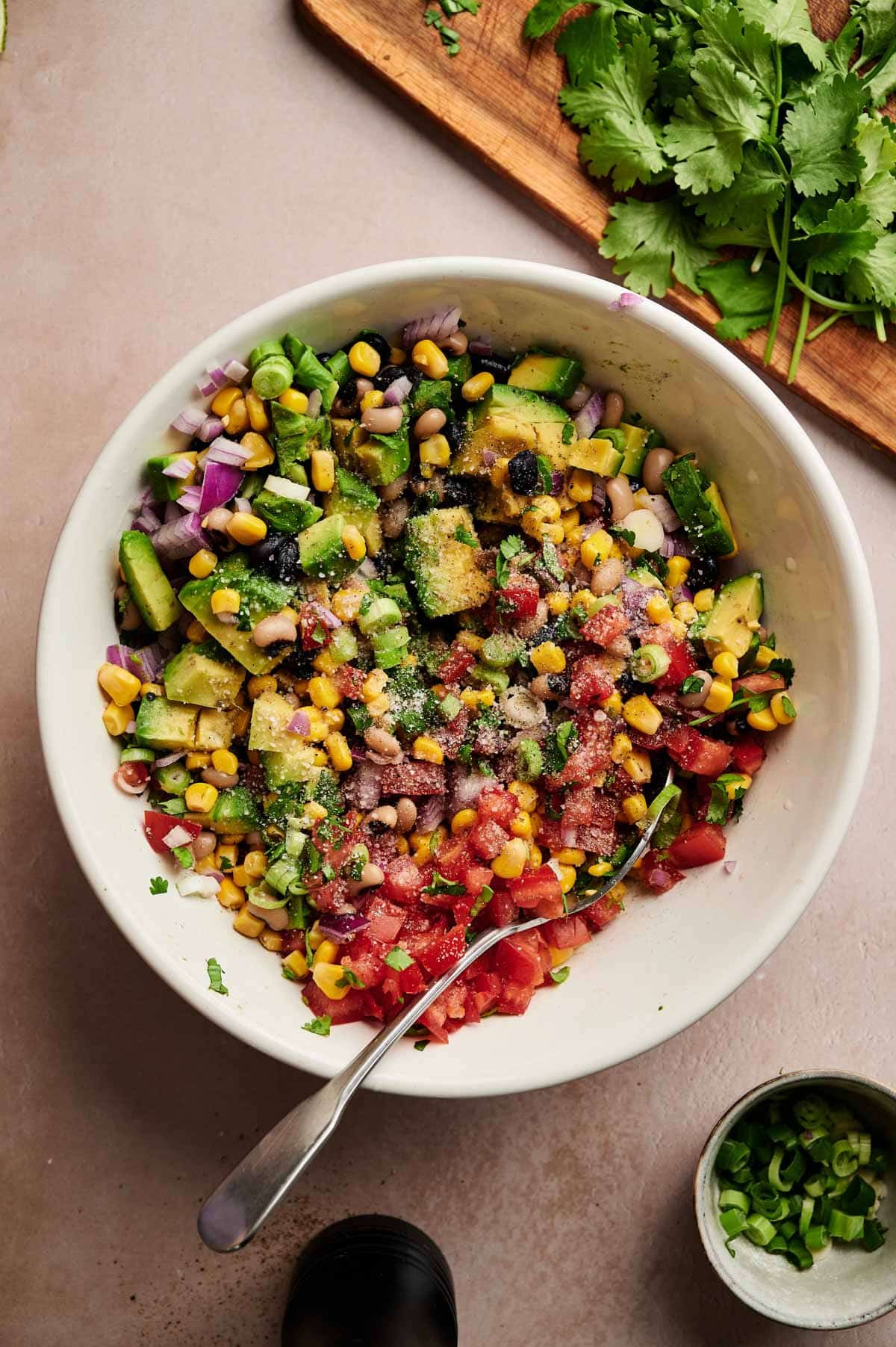 Ingredients for homemade Texas caviar in a white bowl with a spoon sticking out.