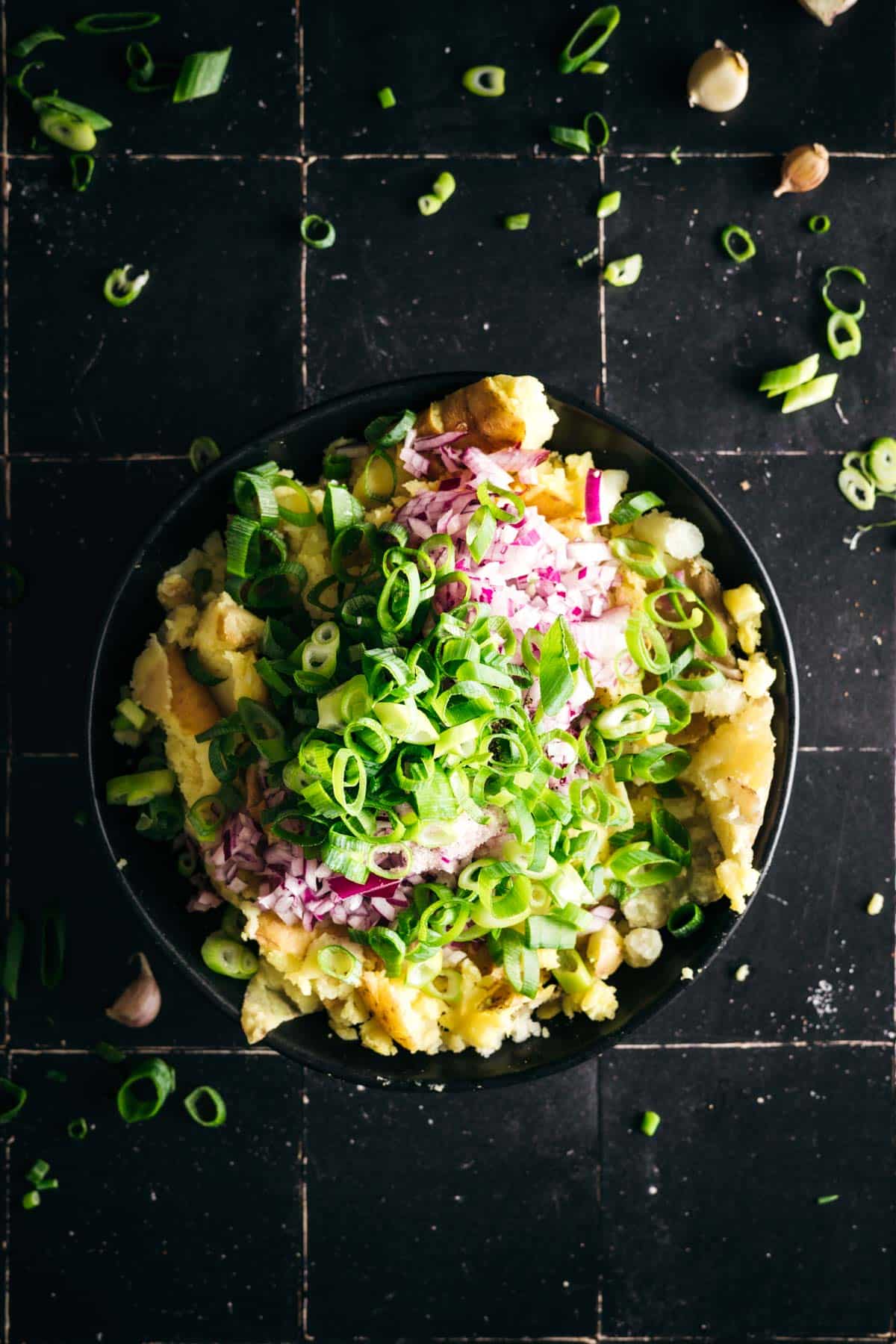 Green onions added to shallow bowl of mashed potatoes.