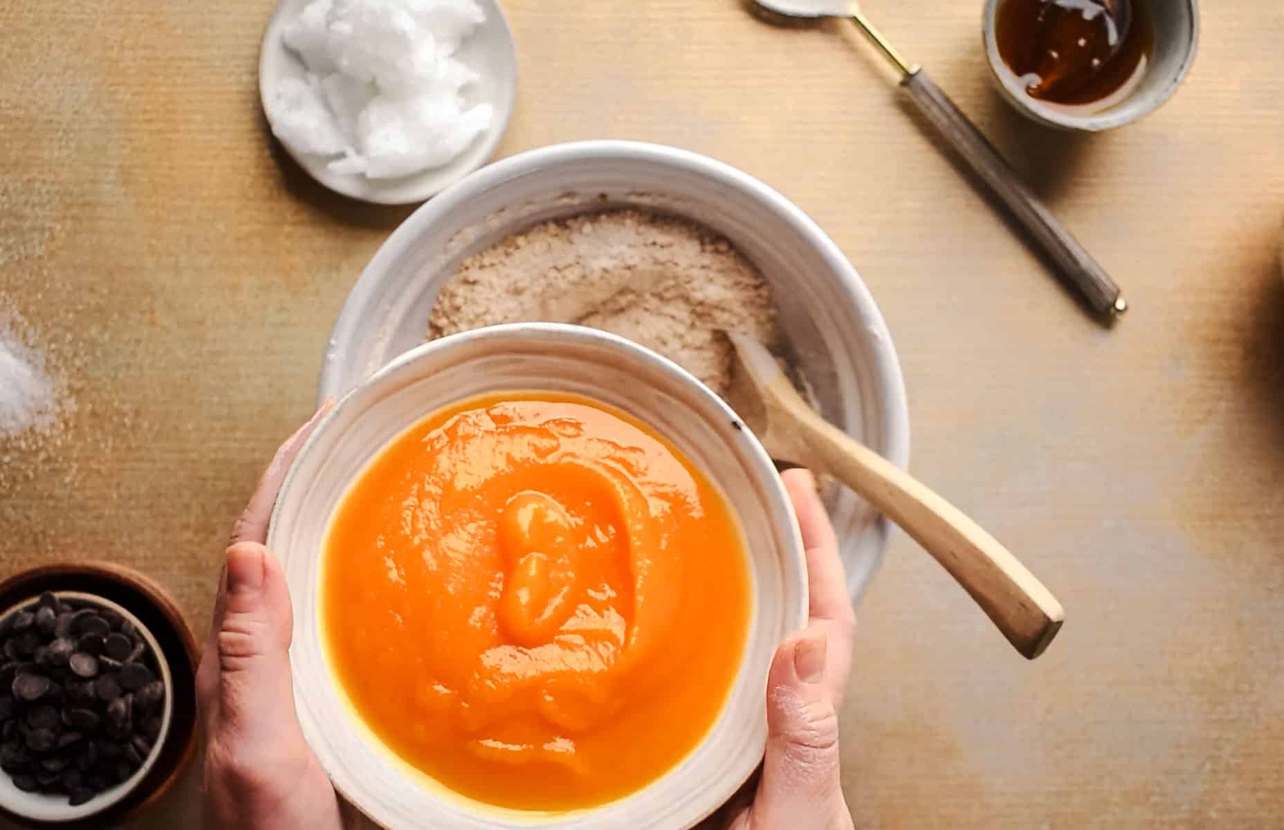 Adding wet ingredients into the large mixing bowl for homemade cookies.