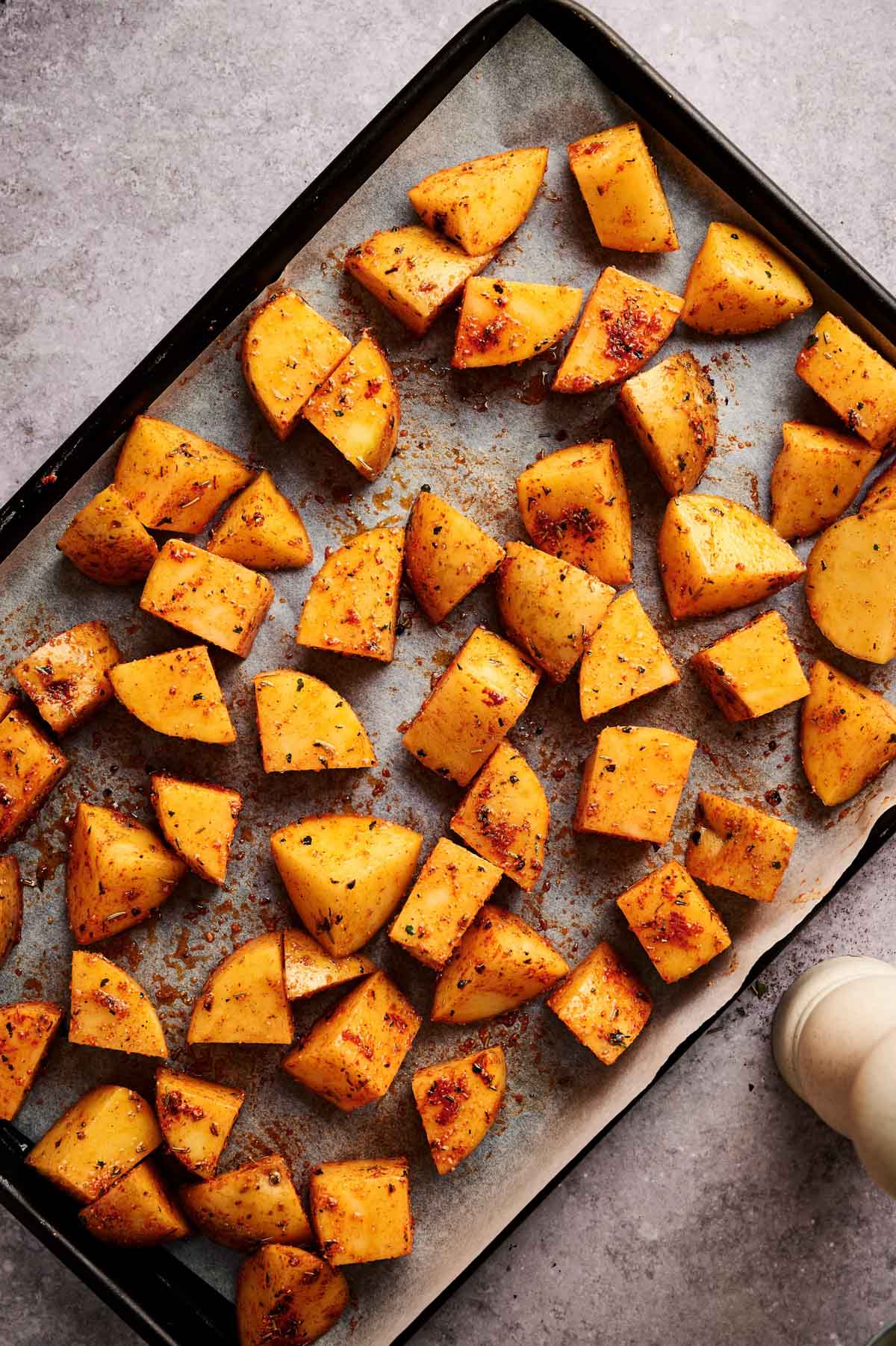 Home fries seasoned and laid out on a baking sheet.