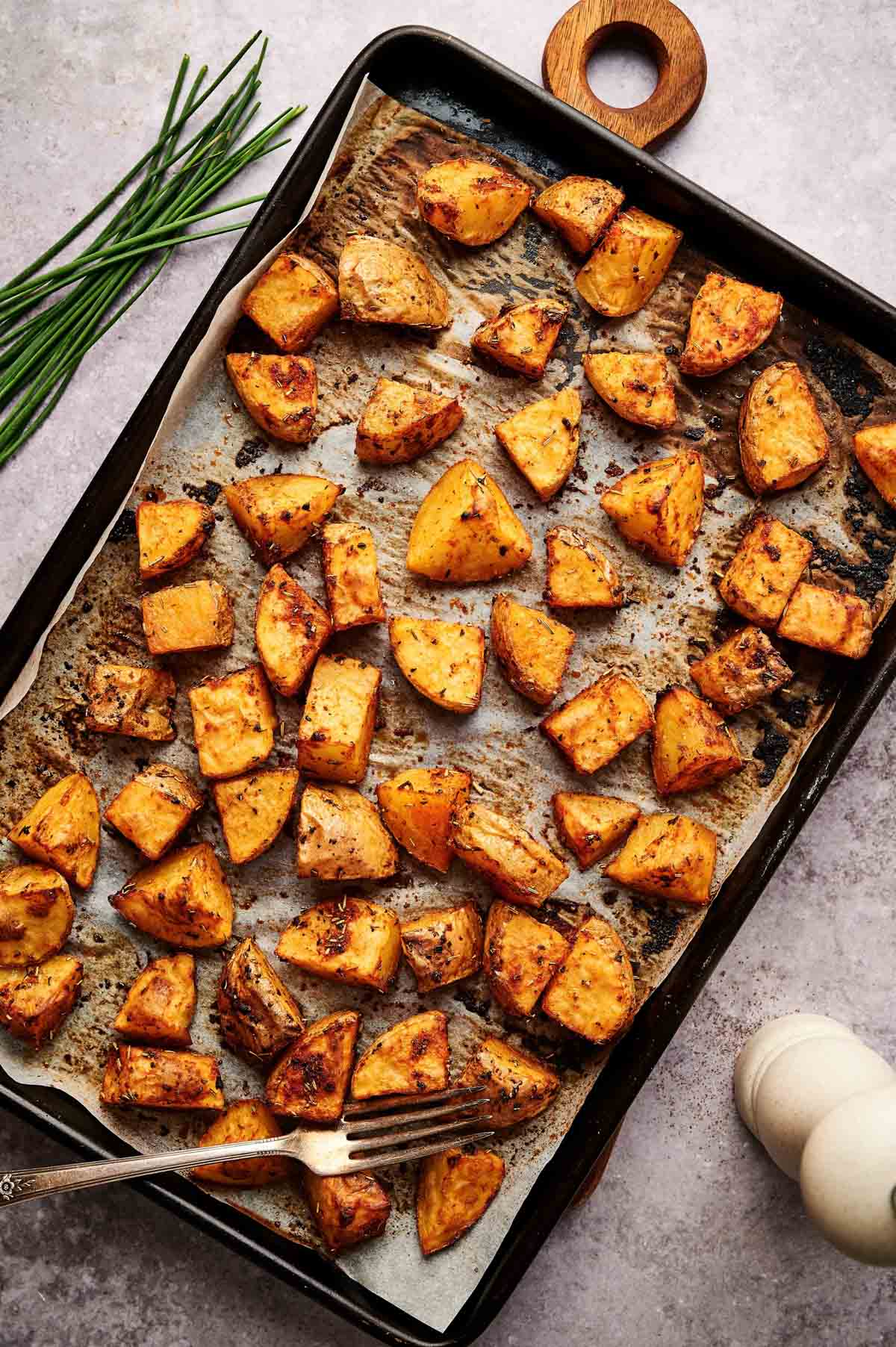 Golden brown home fries on a parchment lined baking sheet.