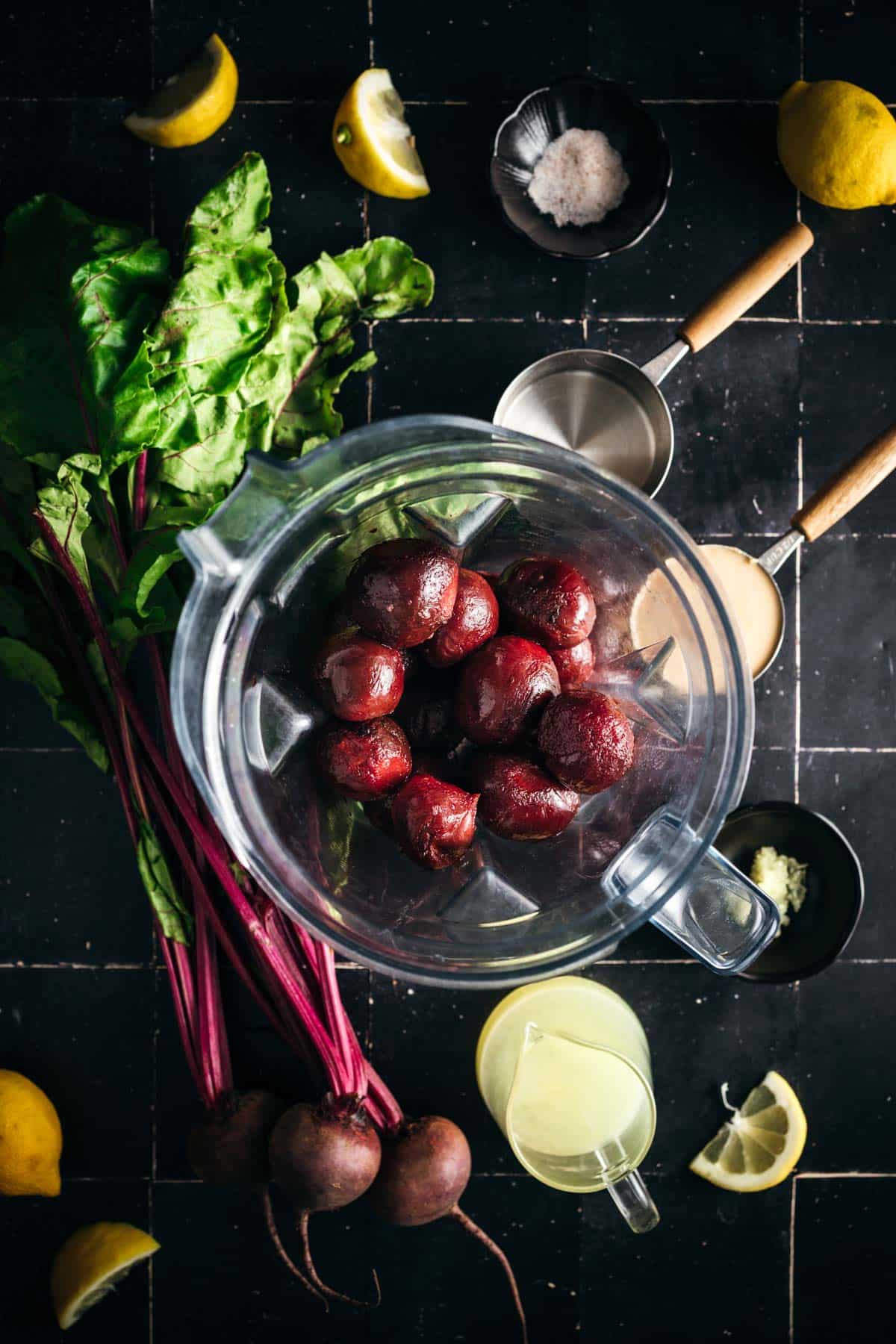 Adding ingredients for beet hummus to a blender.
