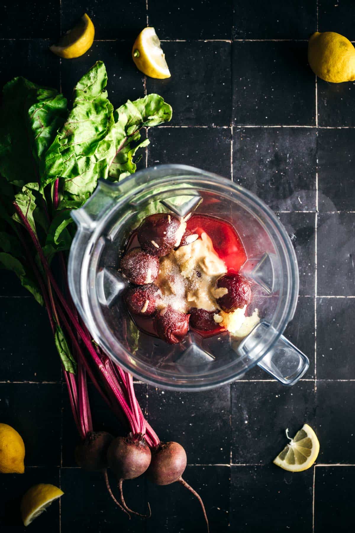 Adding ingredients for beet hummus to a blender.