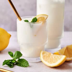 Homemade lemonade with coconut milk in two clear glass cups with metal straws.
