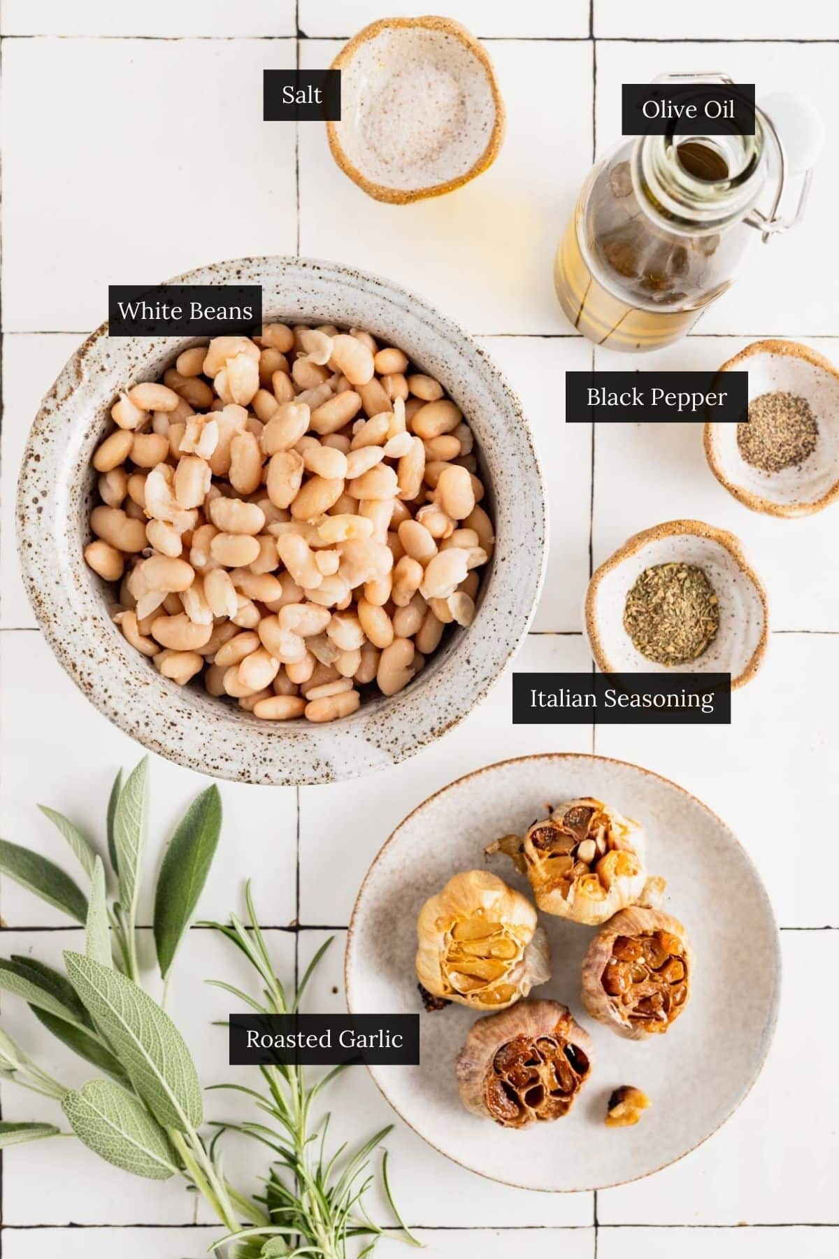 Ingredients for homemade white bean dip on a white tile counter with each ingredient labeled.