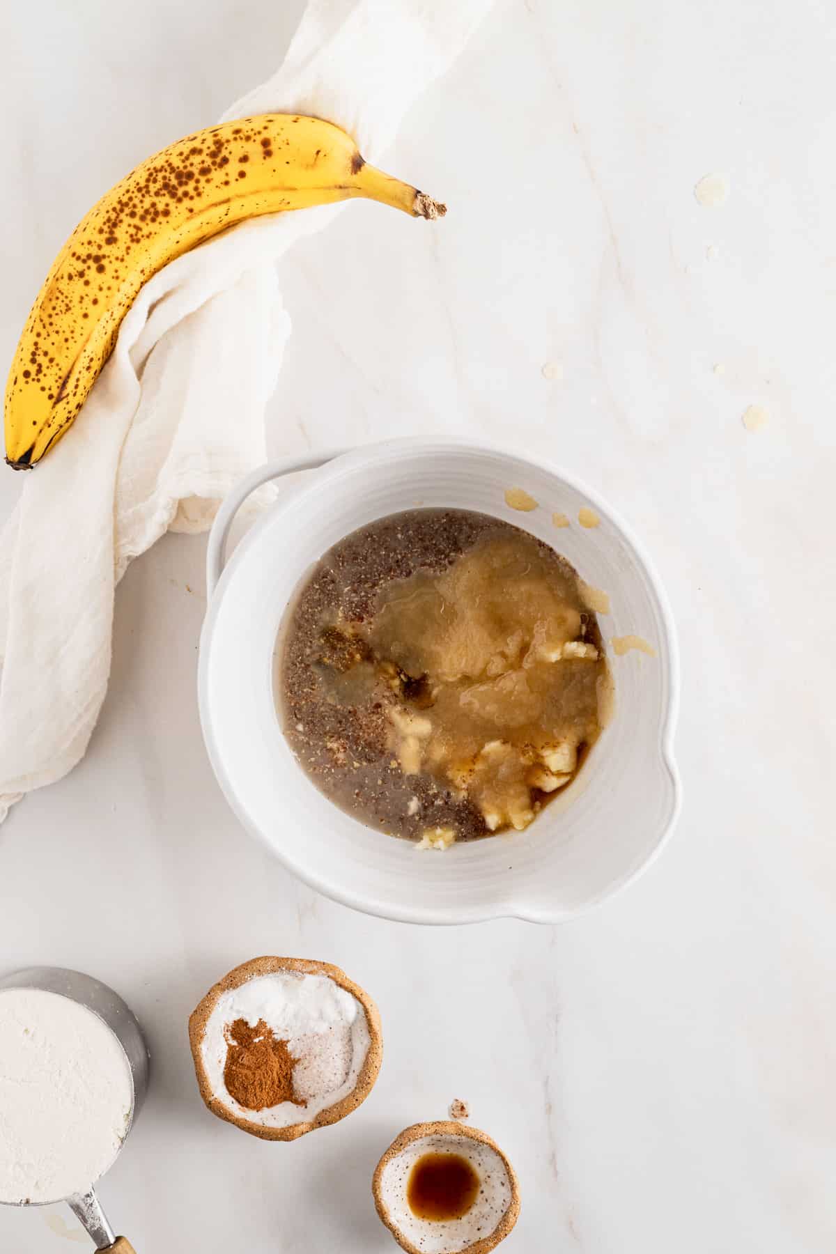 Adding wet ingredients to a bowl for banana bread mini muffins.