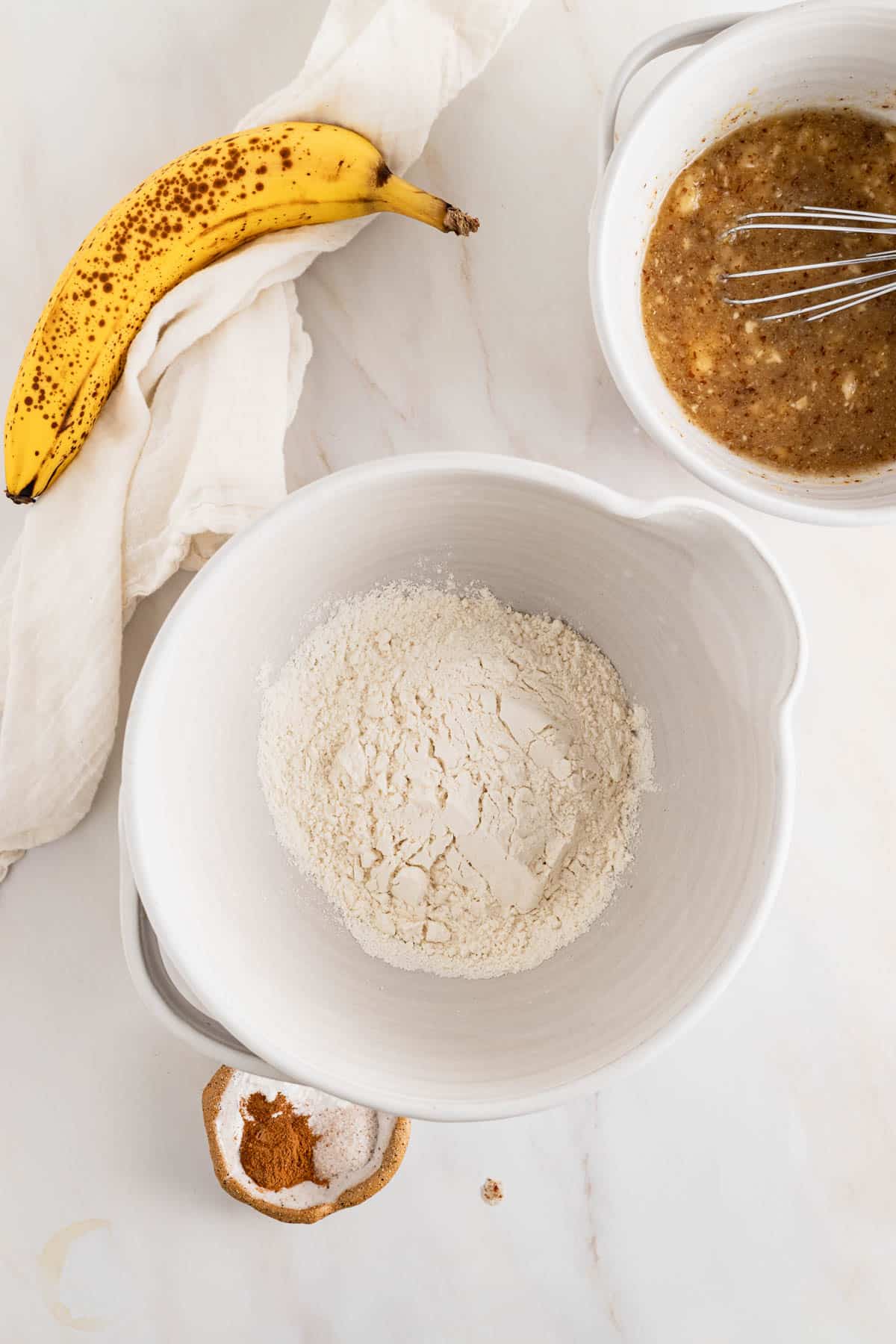 Adding dry ingredients to a medium mixing bowl and whisking them together.