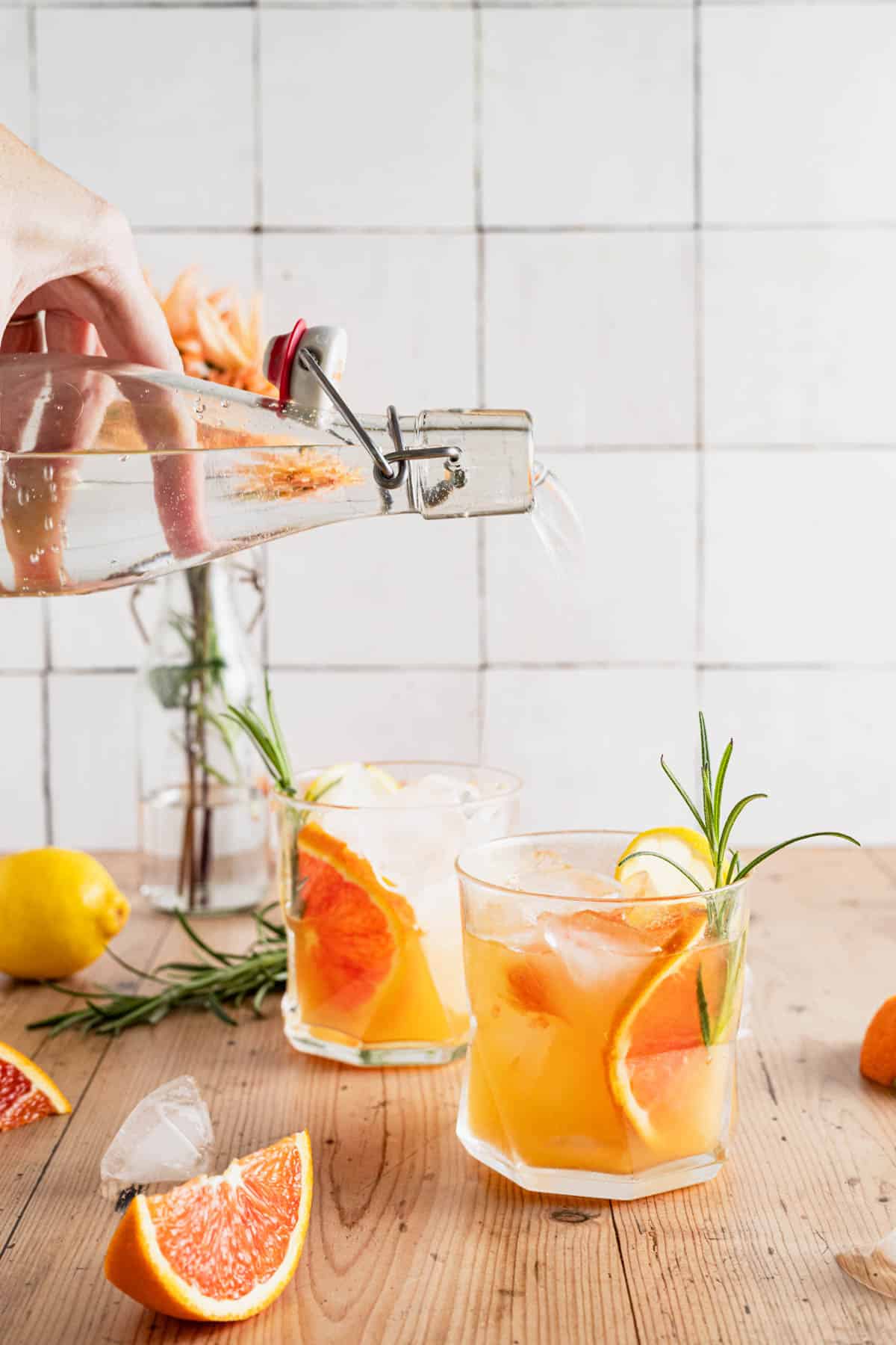 Adding sparking water to orange spritz drink.