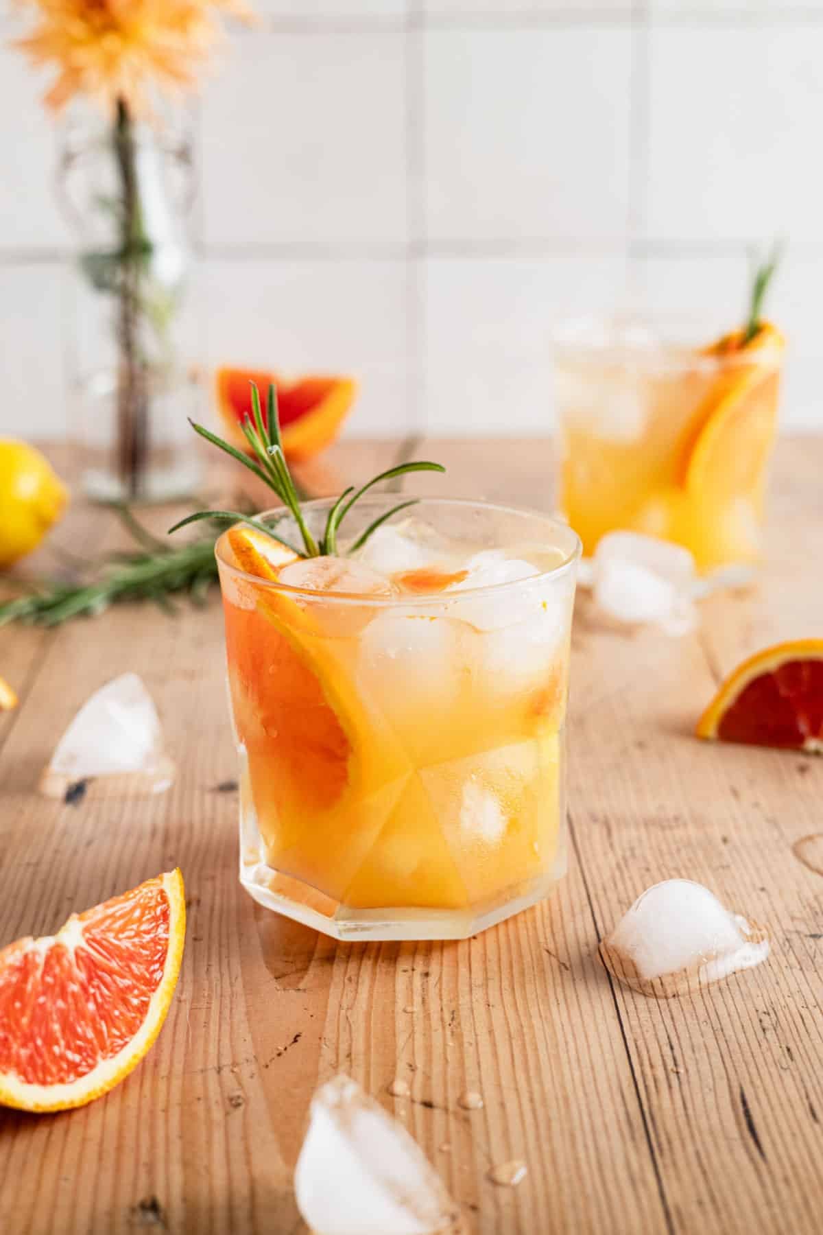 Homemade orange spritz with fresh orange slice and rosemary in glass cup.