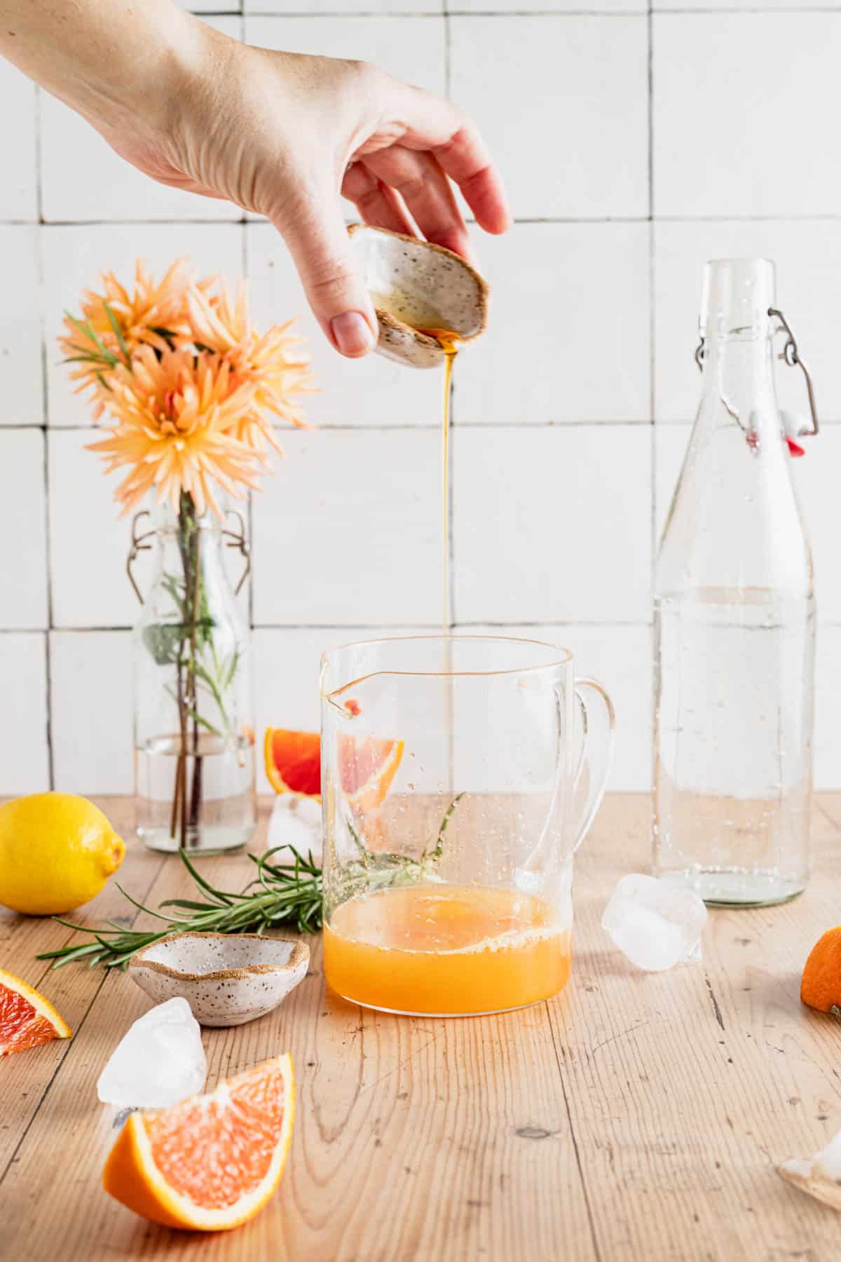 Pouring maple syrup in a liquid measuring cup with citrus juice.