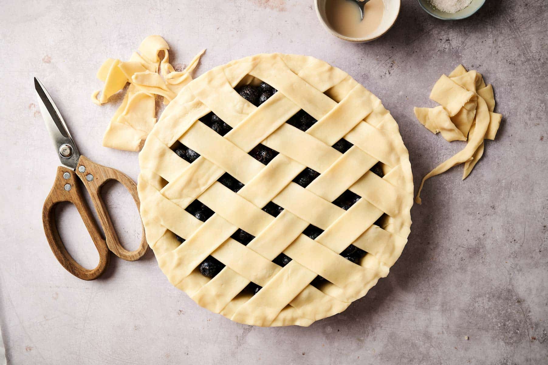 Creating pie crust lattice on top of the berry pie.