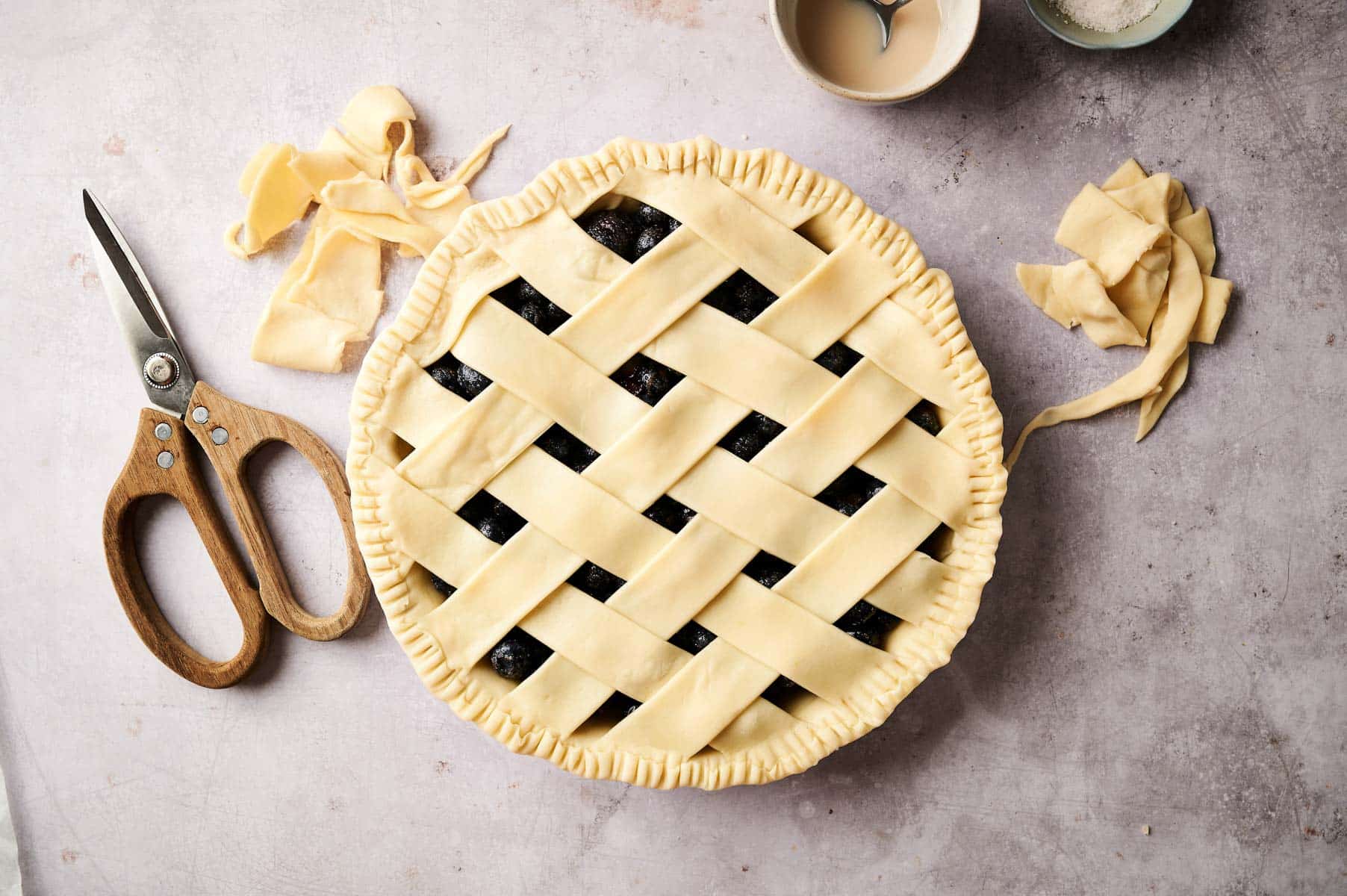 Creating pie crust lattice on top of the berry pie.