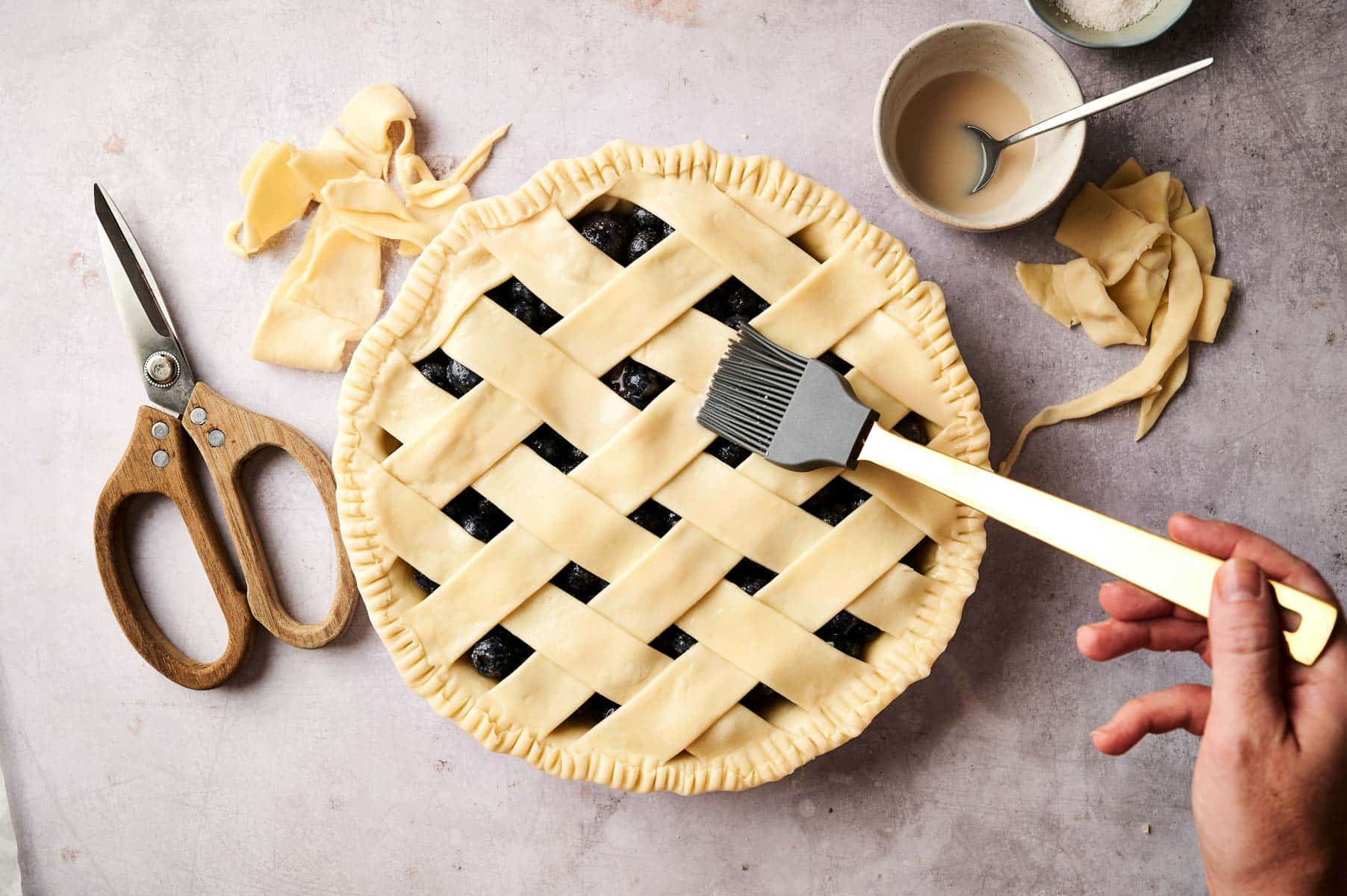 Brushing vegan egg wash on top of pie.