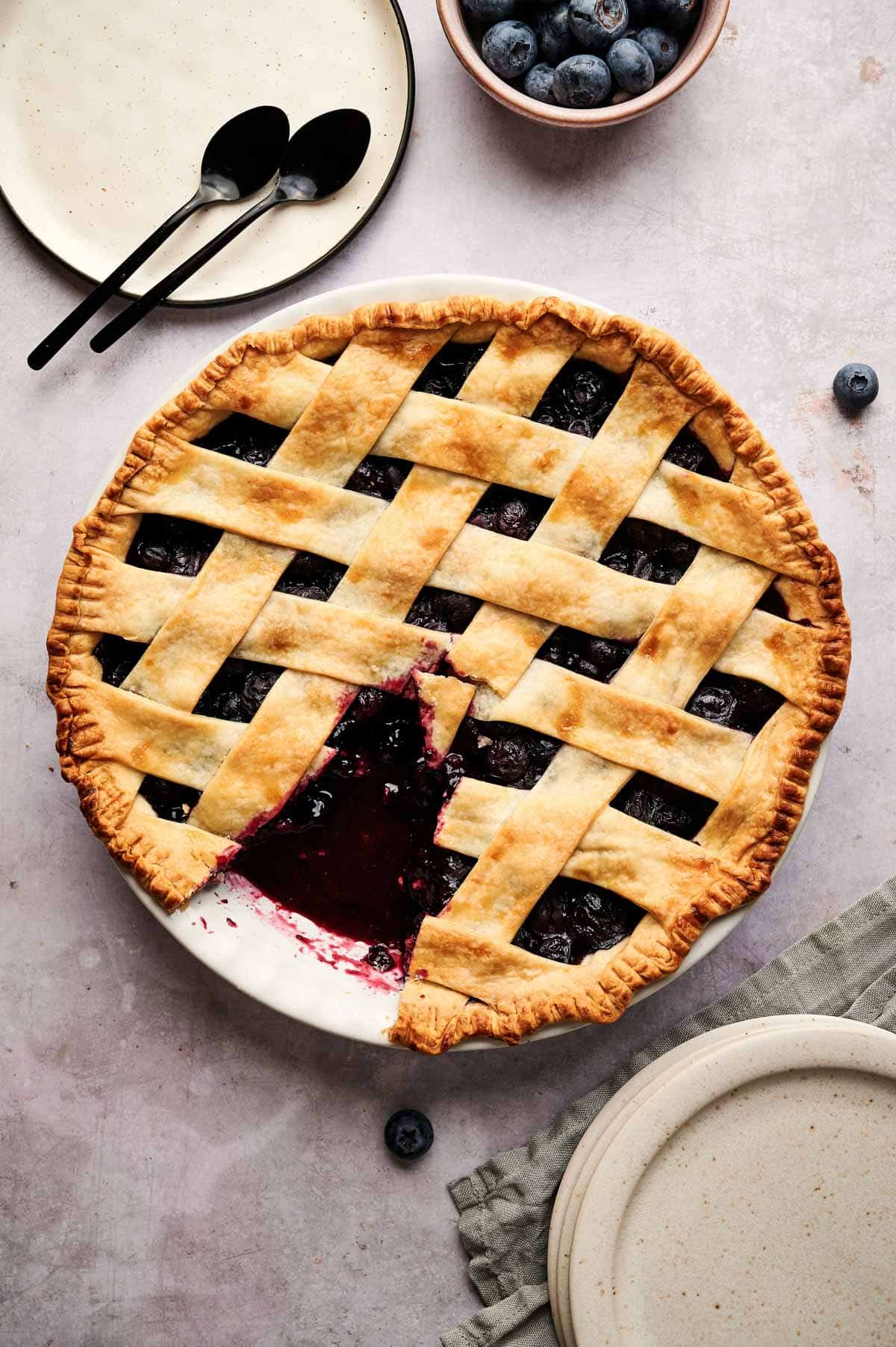 Blueberry pie in a pie pan with a piece cut out.