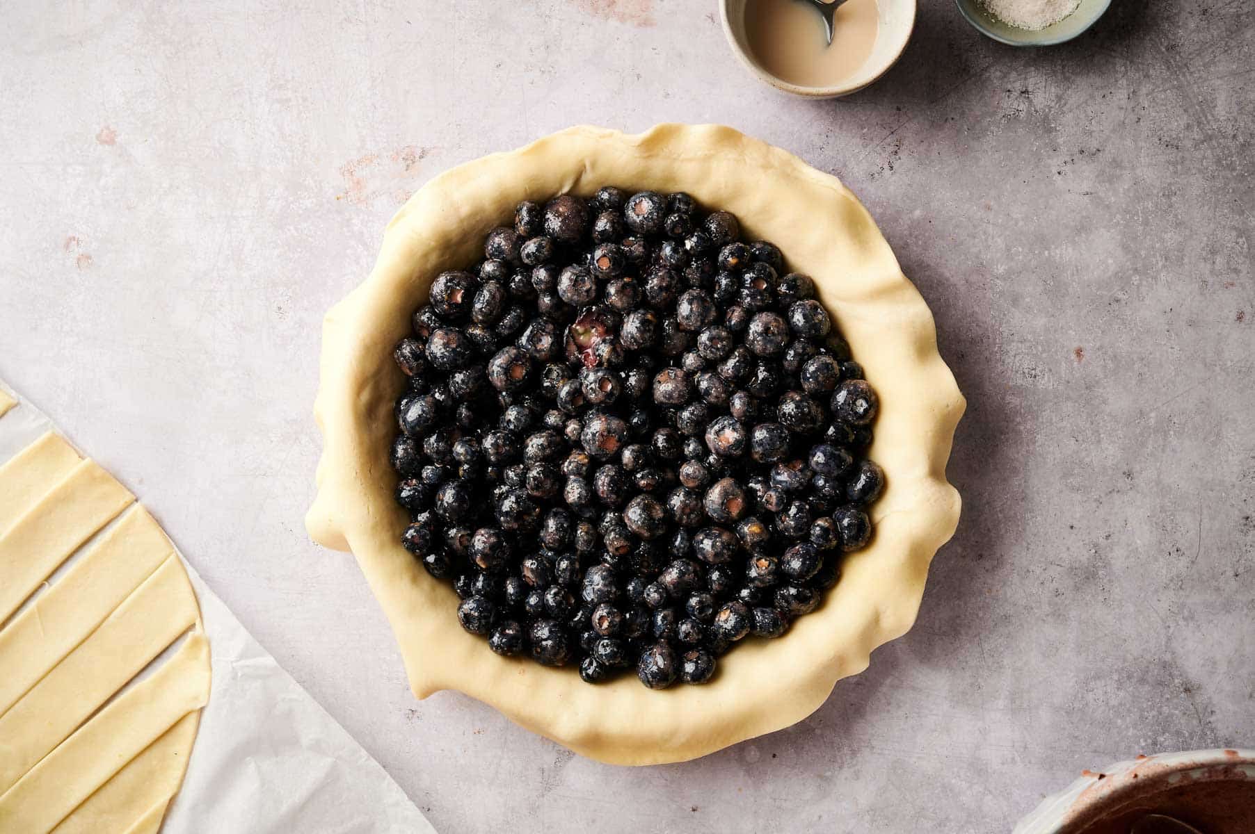 Pie pan lined with pie crust and filled with blueberry filling.