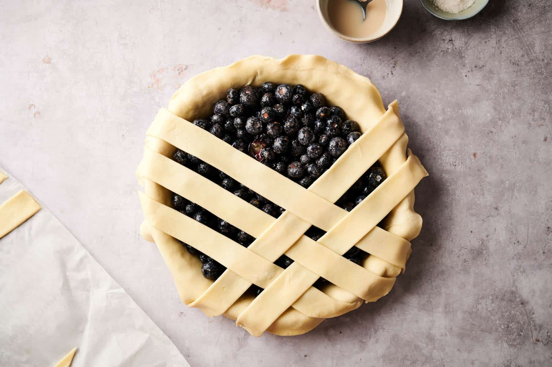 Creating pie crust lattice on top of the berry pie.