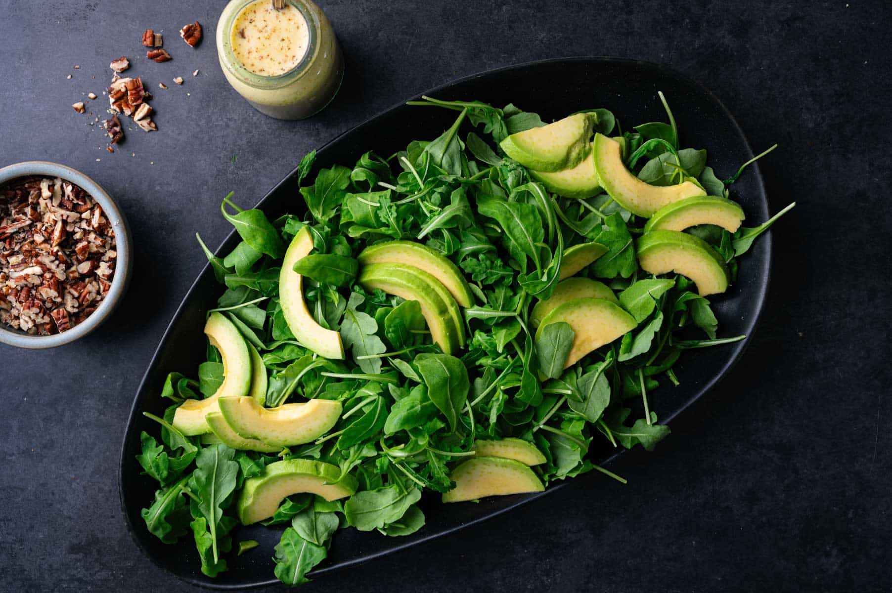 Arugula and avocado spread out on a platter.
