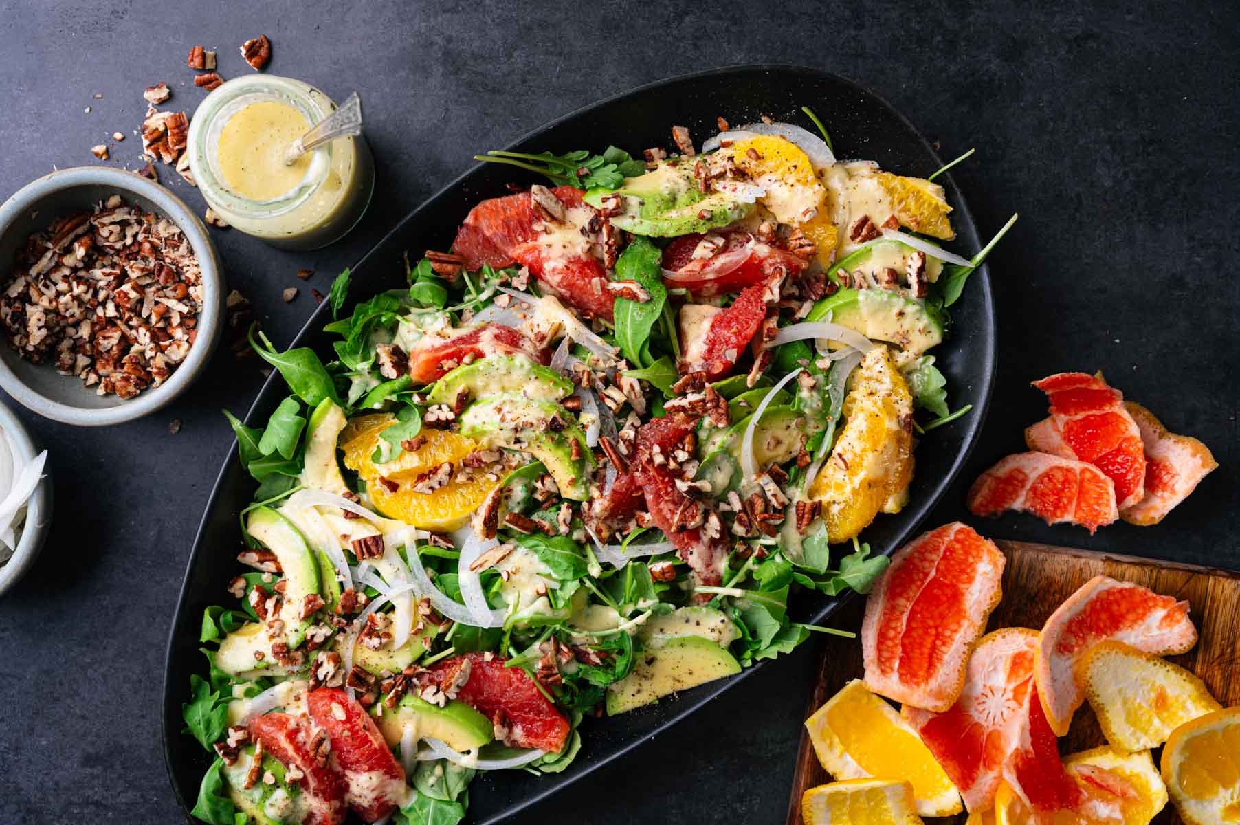 Flavorful arugula and orange salad on a large black serving platter.