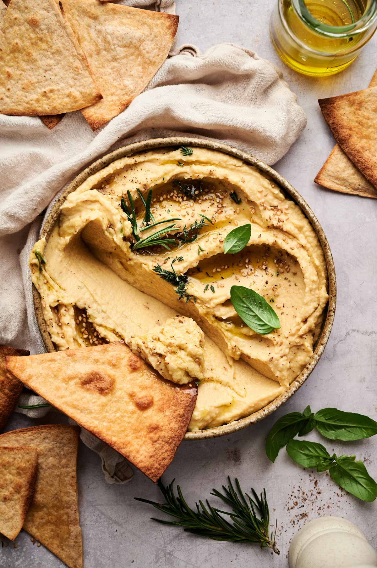 Bowl of hummus with a piece of crispy pita bread on top.