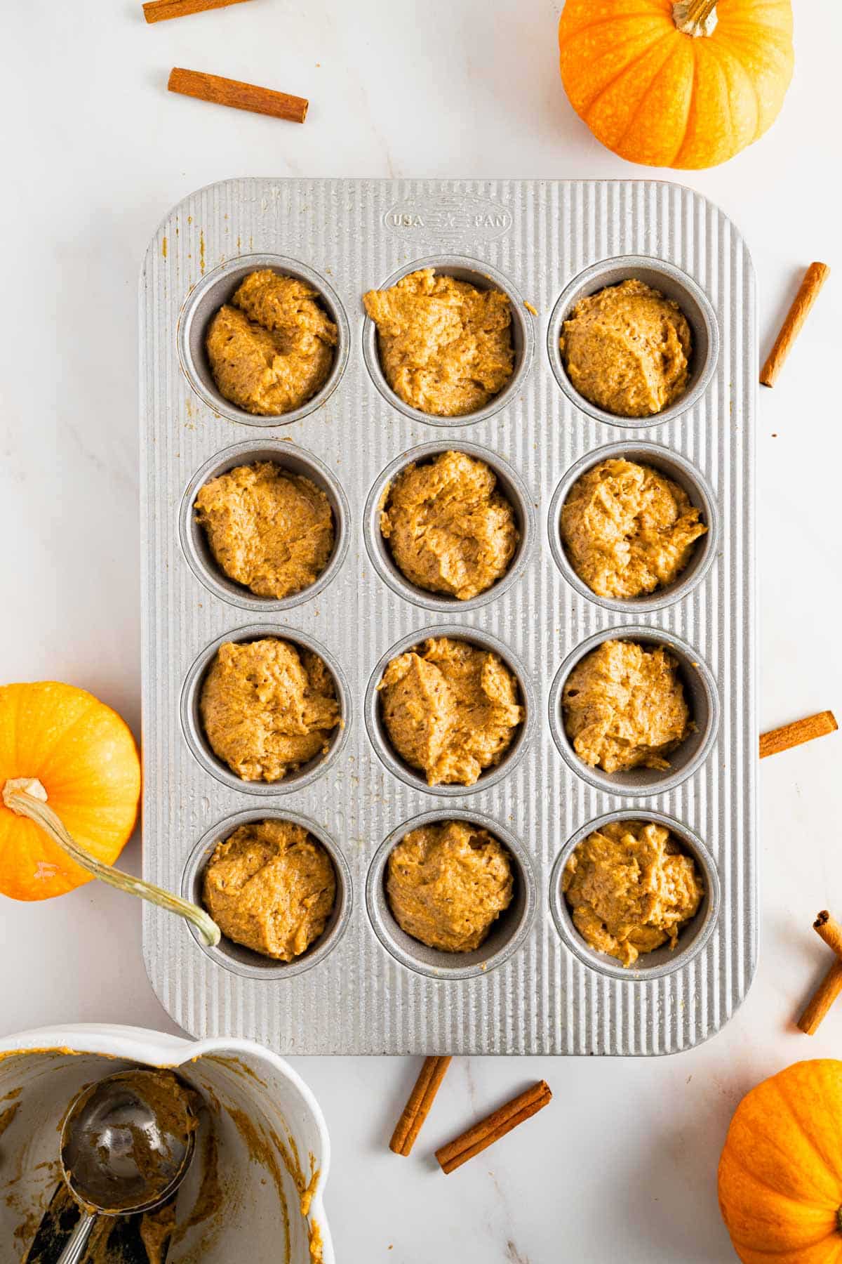 Pumpkin banana muffin batter scooped into the muffin pan.