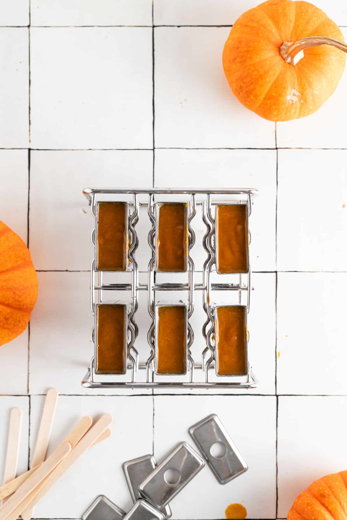 Stainless steel popsicle mold filled with pumpkin spice mixture.