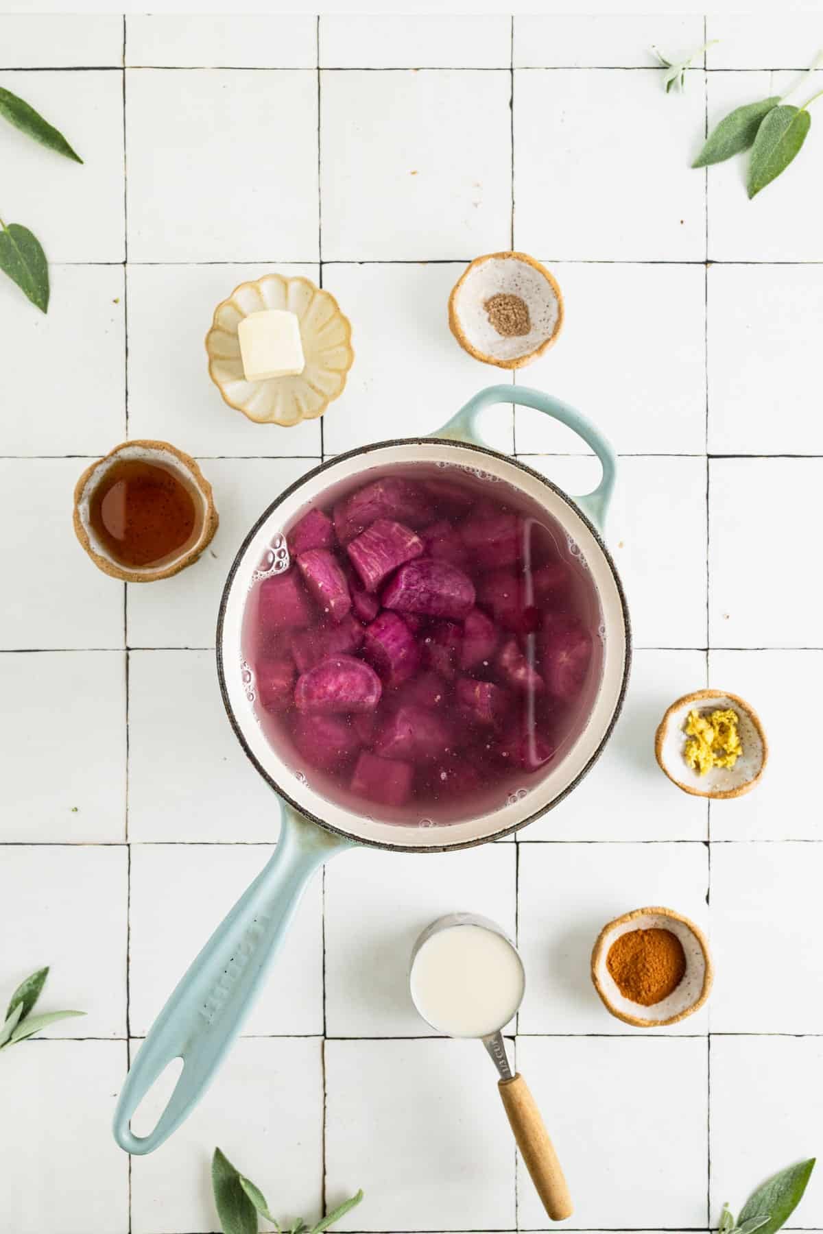 Chopped purple sweet potatoes in a saucepan covered in water cooking.