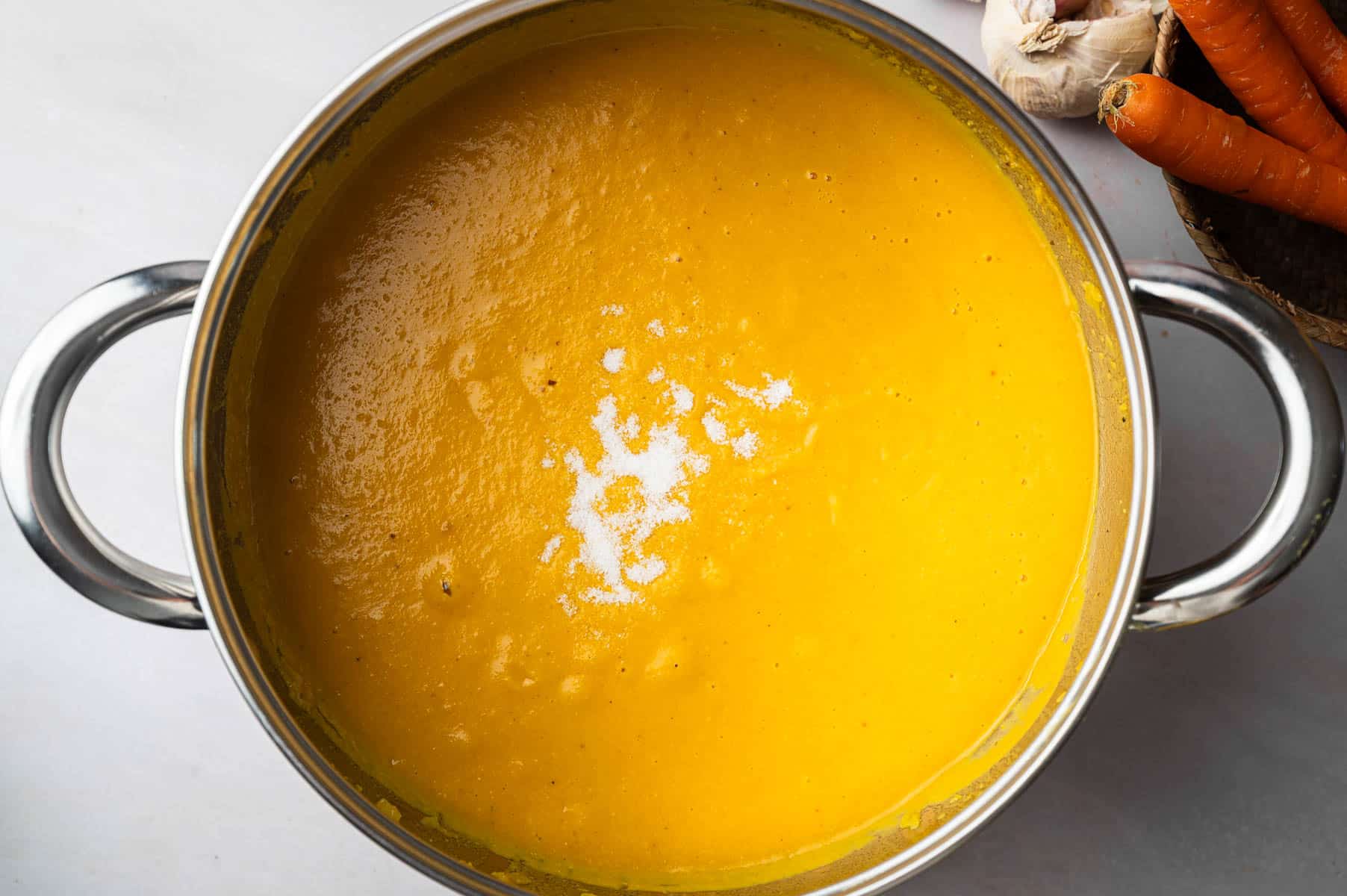 All of the ingredients for carrot and lentil soup in a large stainless steel soup pot on the stove.
