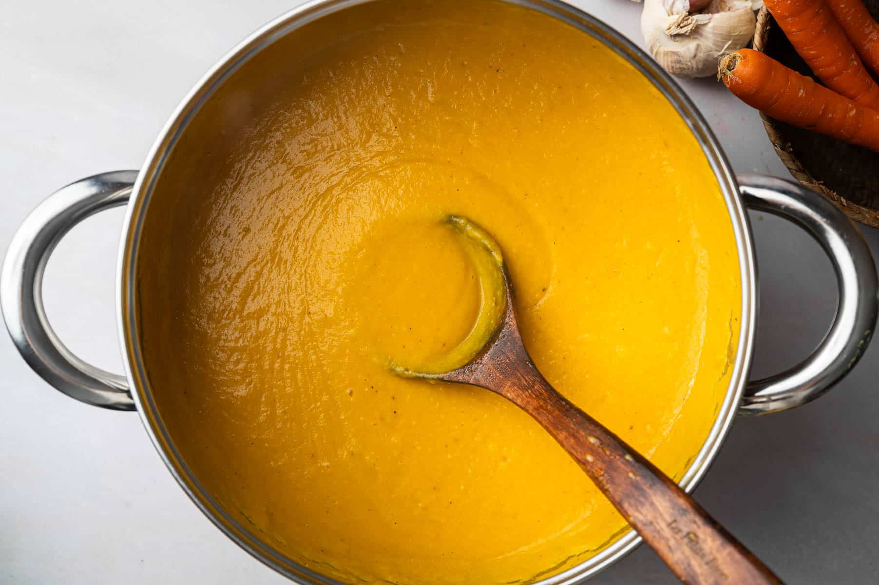 All of the ingredients for carrot and lentil soup in a large stainless steel soup pot on the stove.