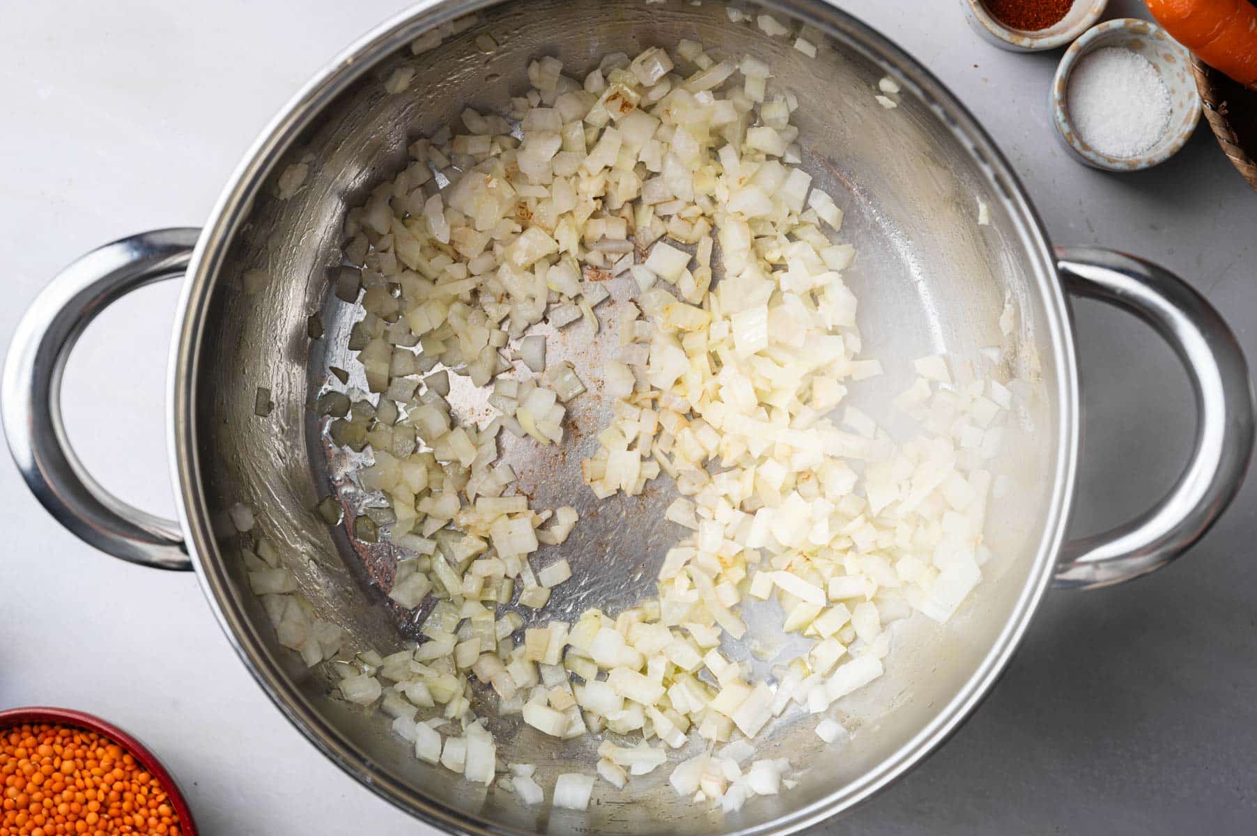 Sauteeing veggie for lentil and carrot soup in a stainless steel pot.