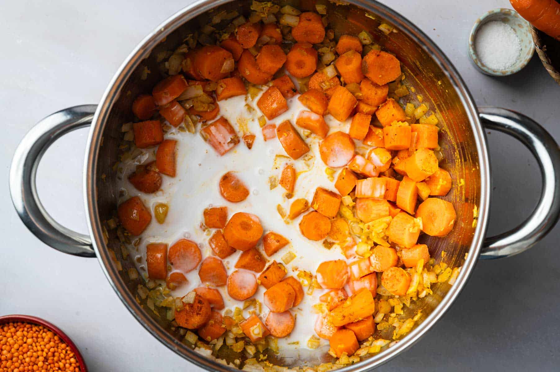 Sauteeing veggie for lentil and carrot soup in a stainless steel pot.
