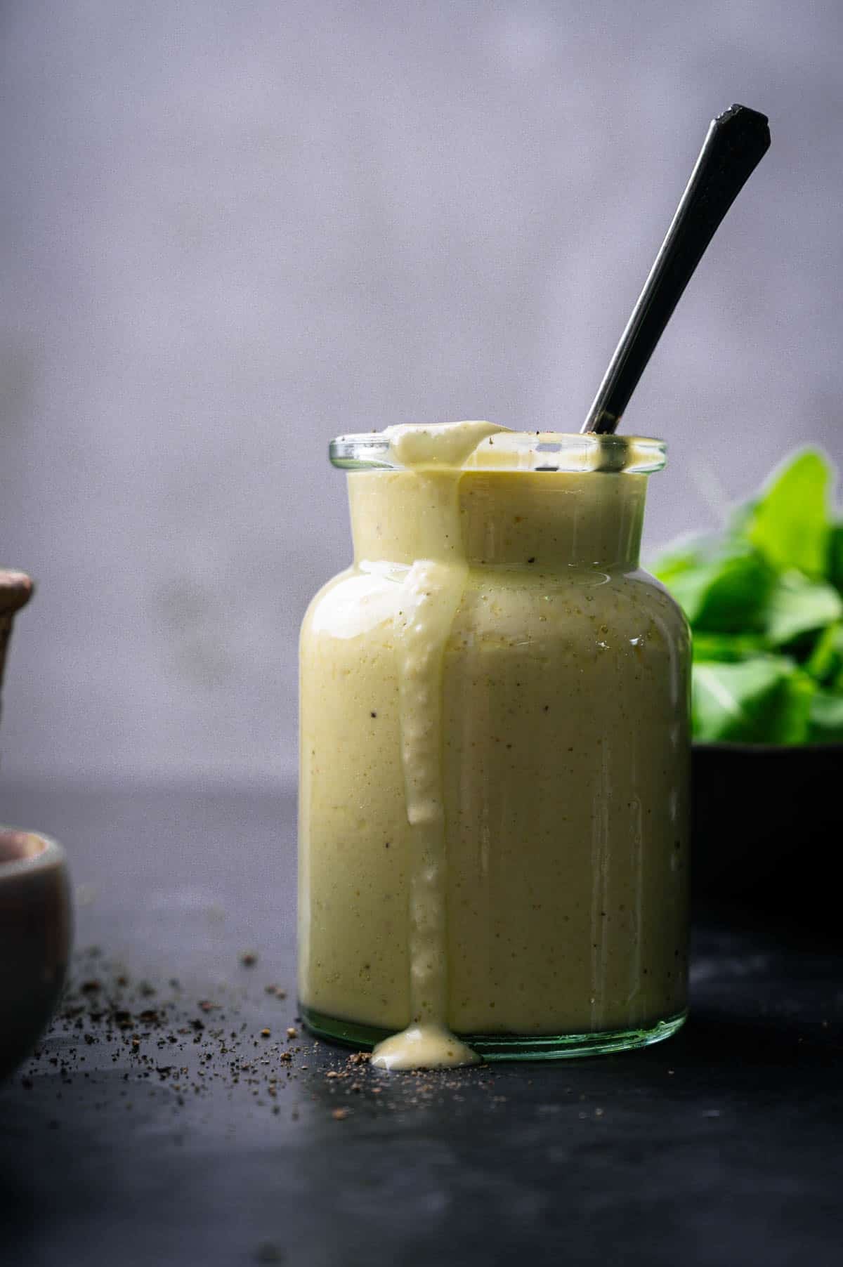 Citrus sweet onion dressing in a glass jar with it dribbling over the side.