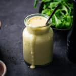 Citrus sweet onion dressing in a glass jar with it dribbling over the side.