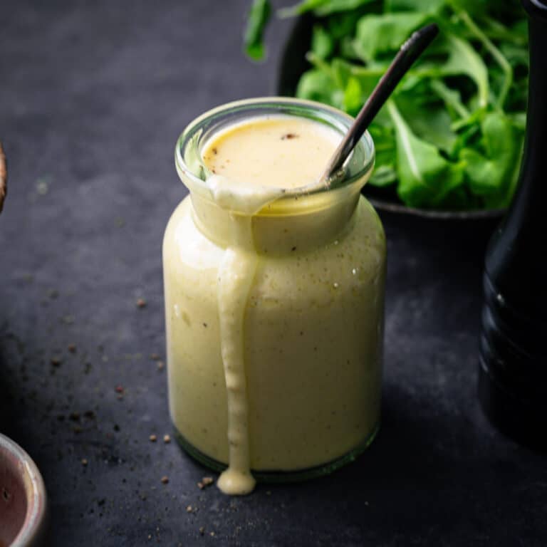 Citrus sweet onion dressing in a glass jar with it dribbling over the side.