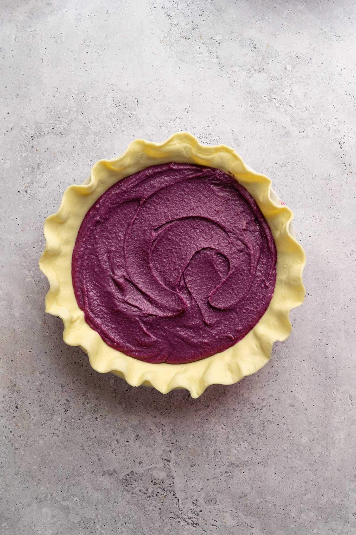 Sweet potato pie filling in the pie crust with the pie edges formed.