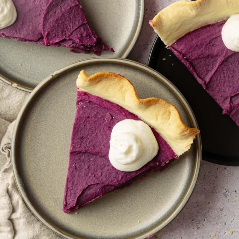 Homemade vegan sweet potato pie slices on plates with whipped cream.