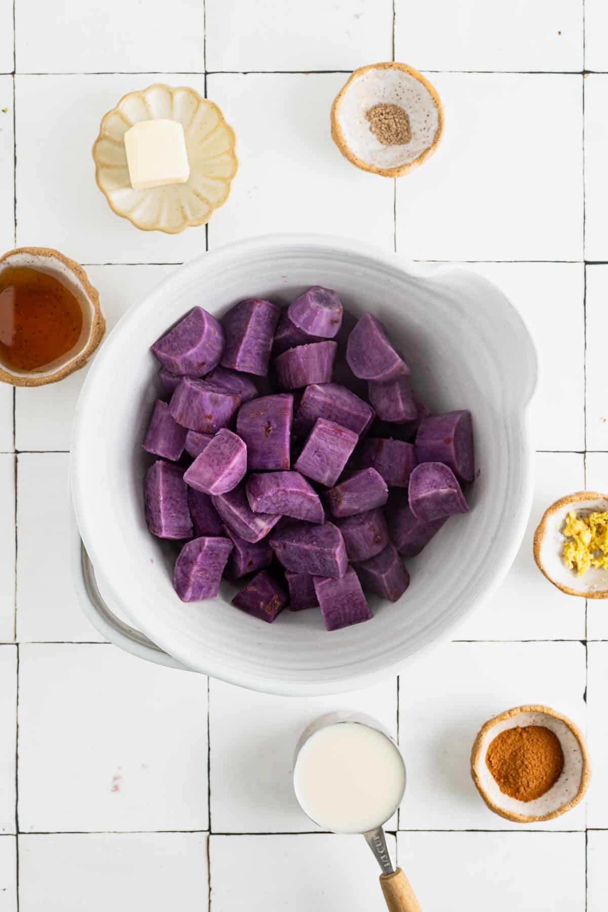 Cooked sweet potato chunks in a large white mixing bowl with spices.