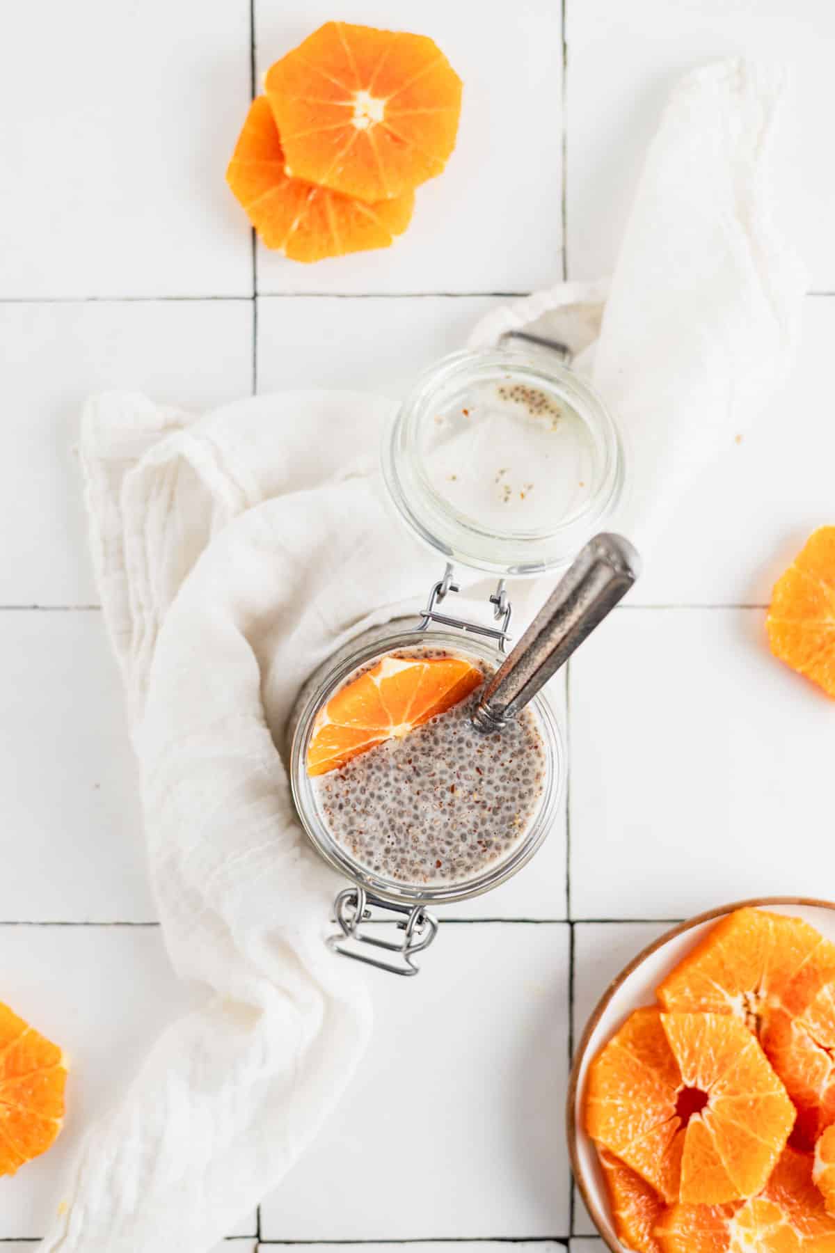 Chia flax pudding with vibrant orange slices in it and around it.