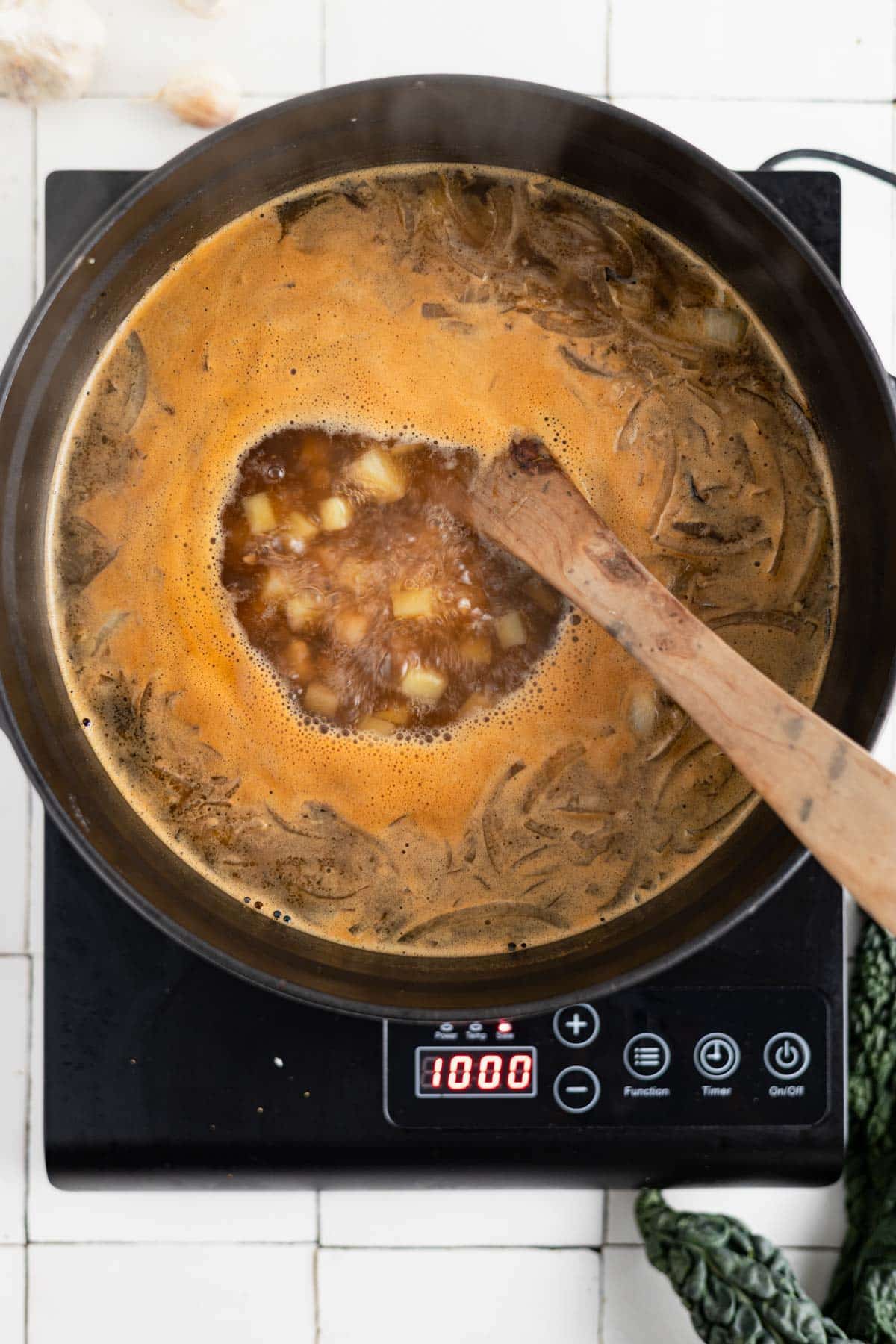 Kale and chickpea soup boiling in a soup pot.