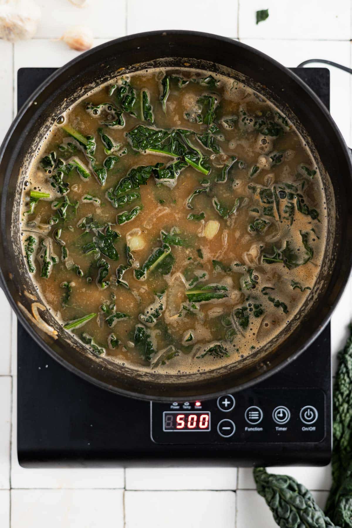 Kale chickpea soup cooking on an induction cooktop.