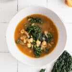 Potato kale soup with chickpeas in a white handmade bowl.