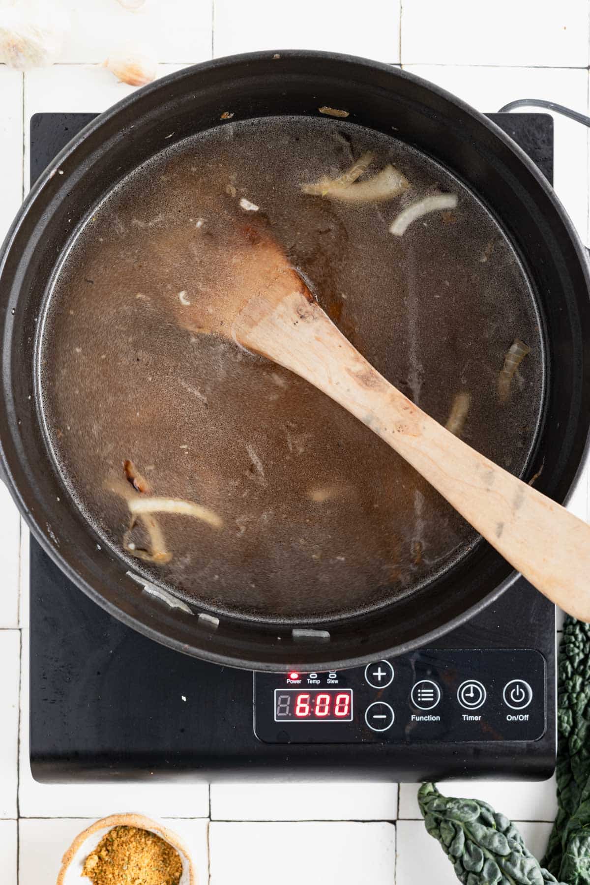 Water added to the pot with a wooden spoon scraping the fond from the bottom.