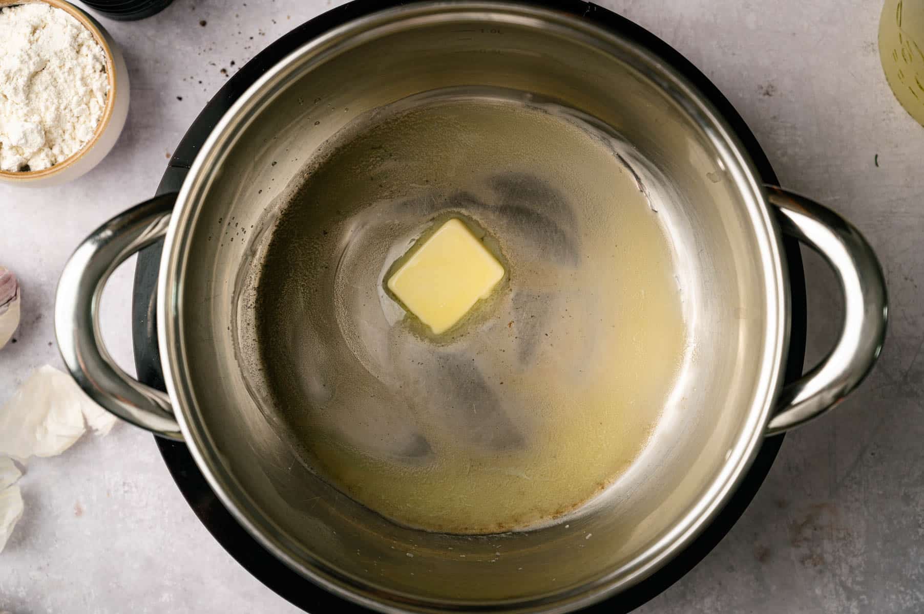 Butter melting in a stainless steel pot.