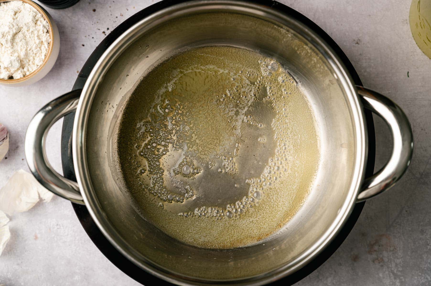 Butter melting in a stainless steel pot.