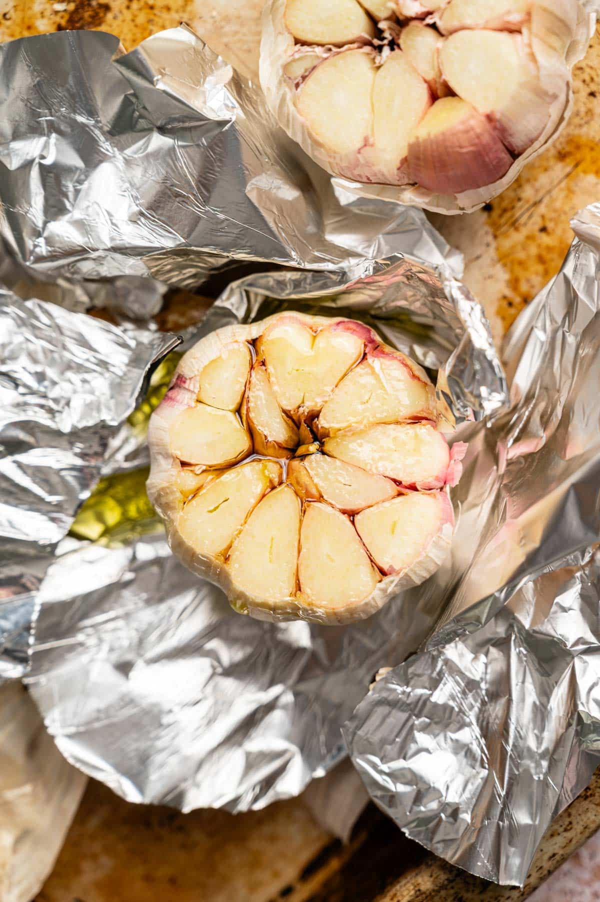 Prepared garlic bulb in foil with oil drizzled on top.